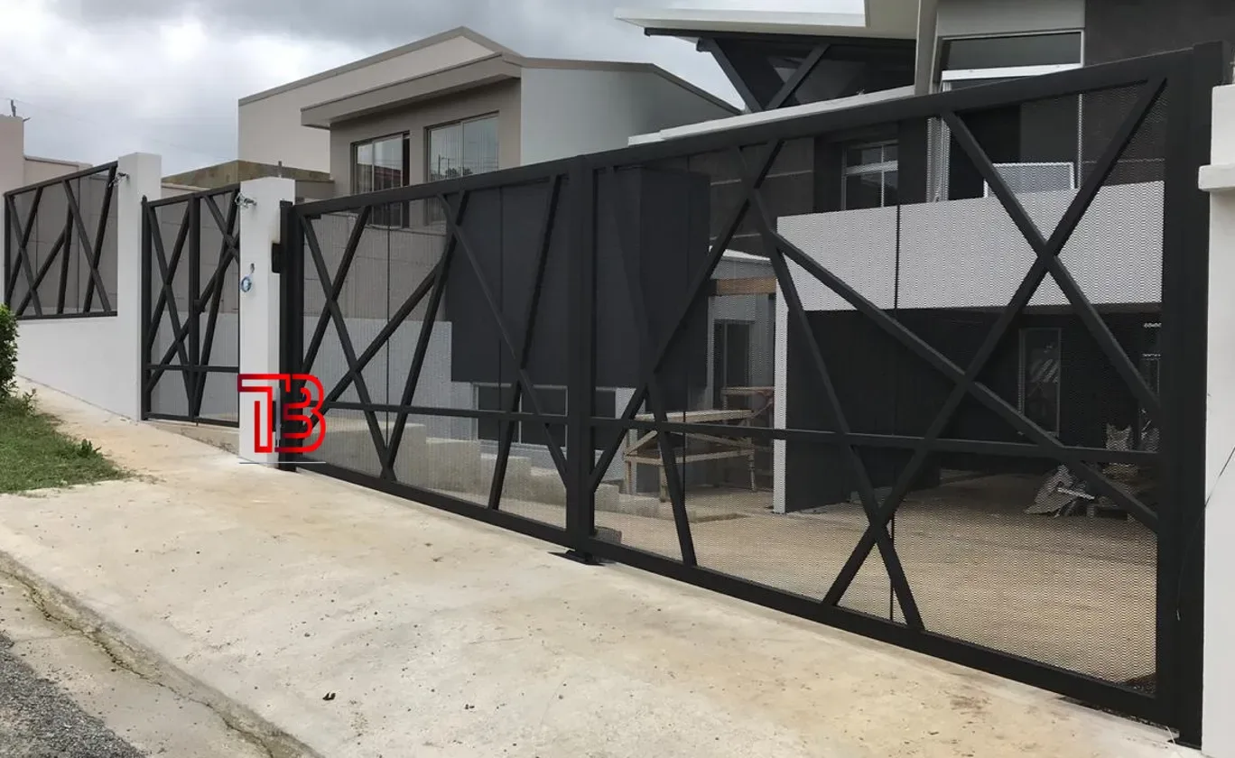 Portón corredizo negro con diseño geométrico y malla metálica realizado por Taller Industrial Brenes